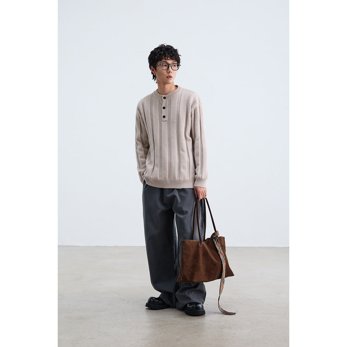 Model wearing a light beige ribbed sweater with a three-button placket, paired with dark wide-leg trousers.