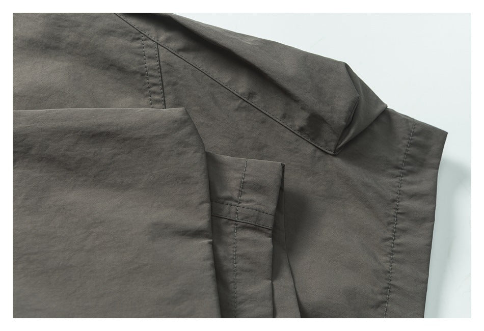 Close-up of charcoal-gray trousers showing overlapping panels, a pocket edge, and stitched seams.