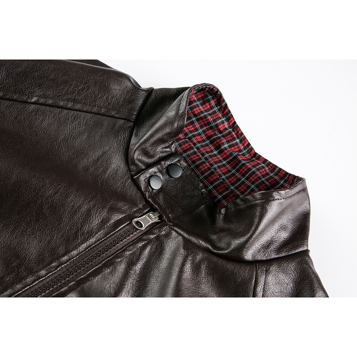 Close-up of a dark brown jacket collar with red-and-black plaid lining, snap buttons, and a diagonal zipper.