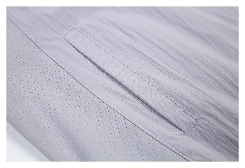 Close-up of a light gray jacket showing fine grid fabric, perforated panel, and stitched flap.