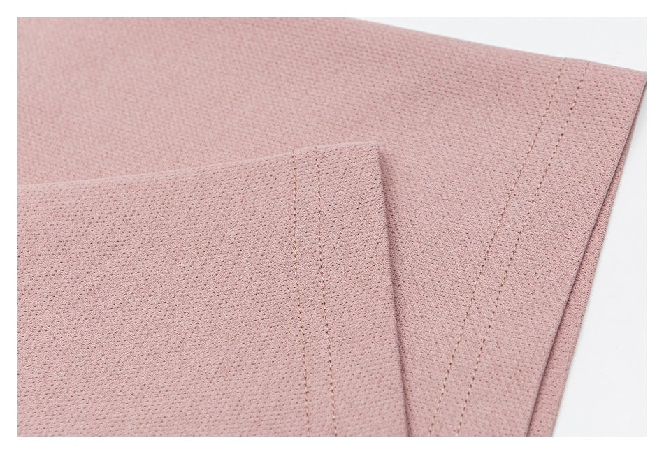Close-up of dusty rose perforated fabric with overlapping stitched edges and a finished seam.