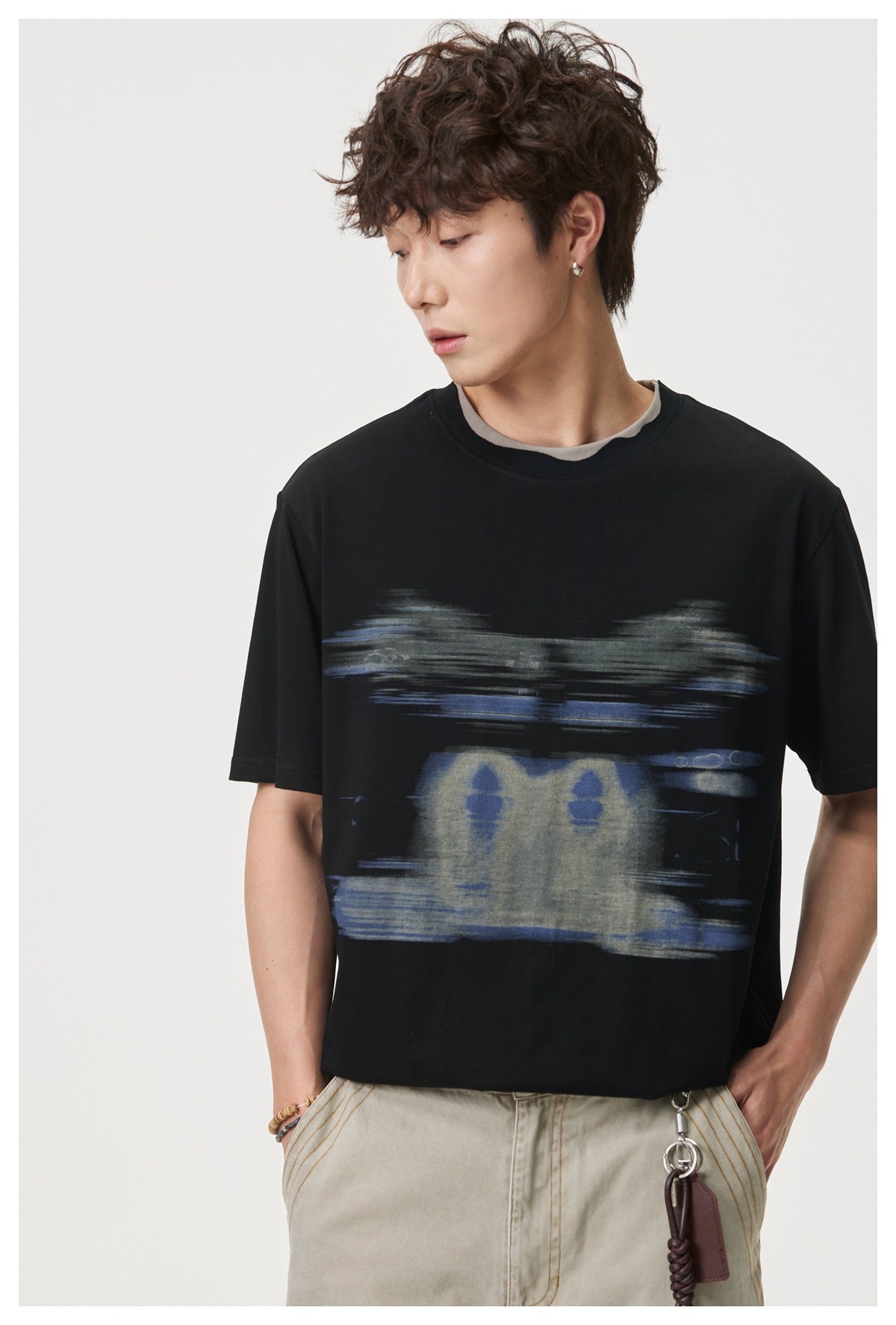 Model wearing a black T-shirt with a large abstract gray and blue brushstroke graphic across the chest.
