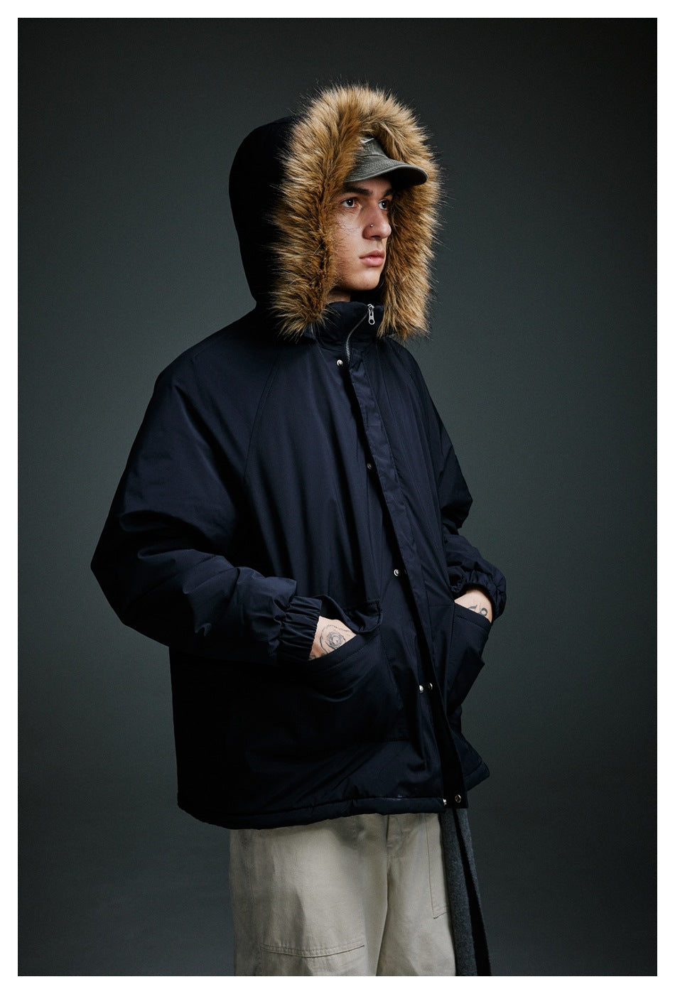 Model wearing a dark navy hooded jacket with tan fur trim, snap closure and front pockets.