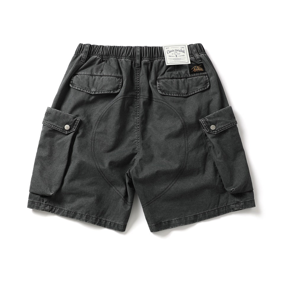 Back view of charcoal cargo shorts with an elastic waist, two flap pockets, and large snap-button side pockets.