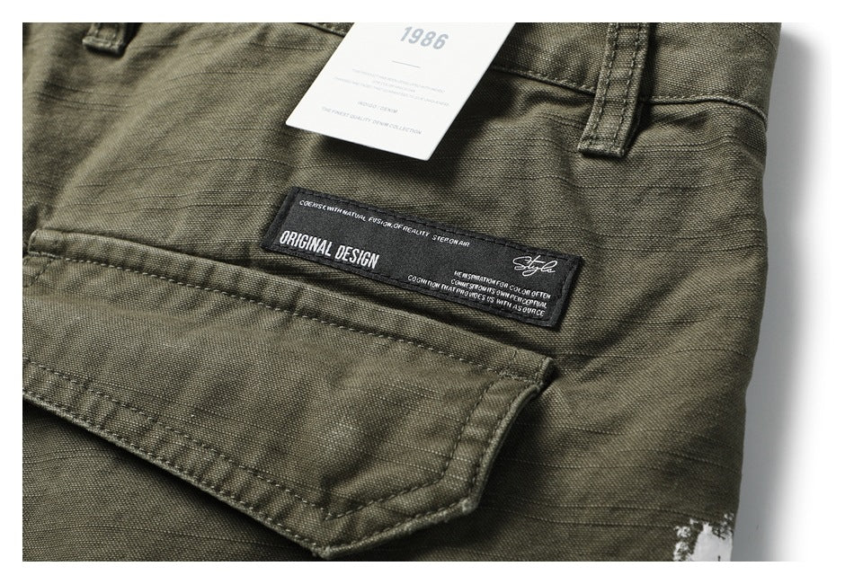 Close-up of olive trousers showing a sewn black label and a white hangtag.