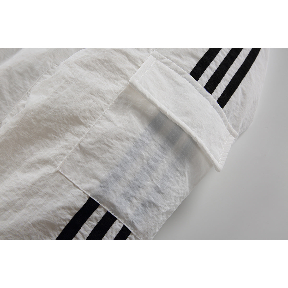 Close-up of a white jacket pocket and black sleeve stripes.