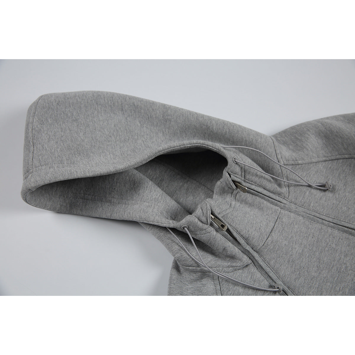 Close-up of a heather gray hoodie showing its hood, drawstrings, and front zipper.