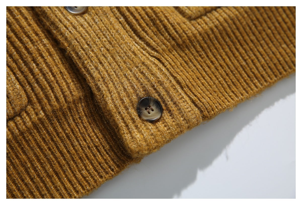 Close-up of a dark button, ribbed knit fabric, and hem on a mustard-brown cardigan.