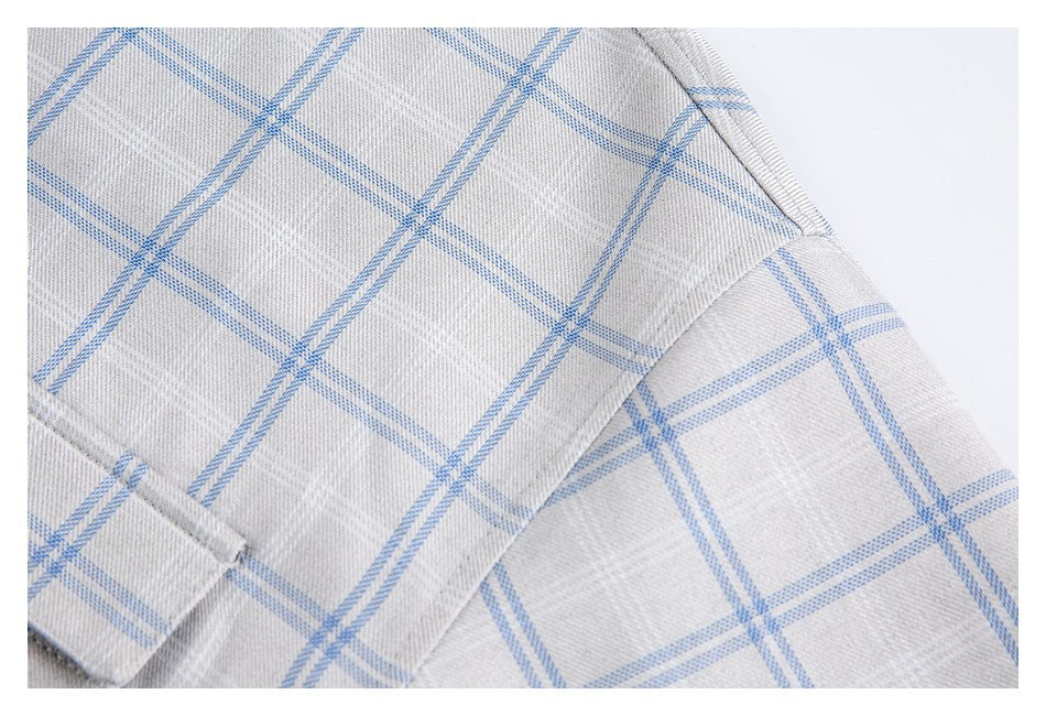 Close-up of light gray shirt fabric with a blue windowpane check and stitched folded edges.