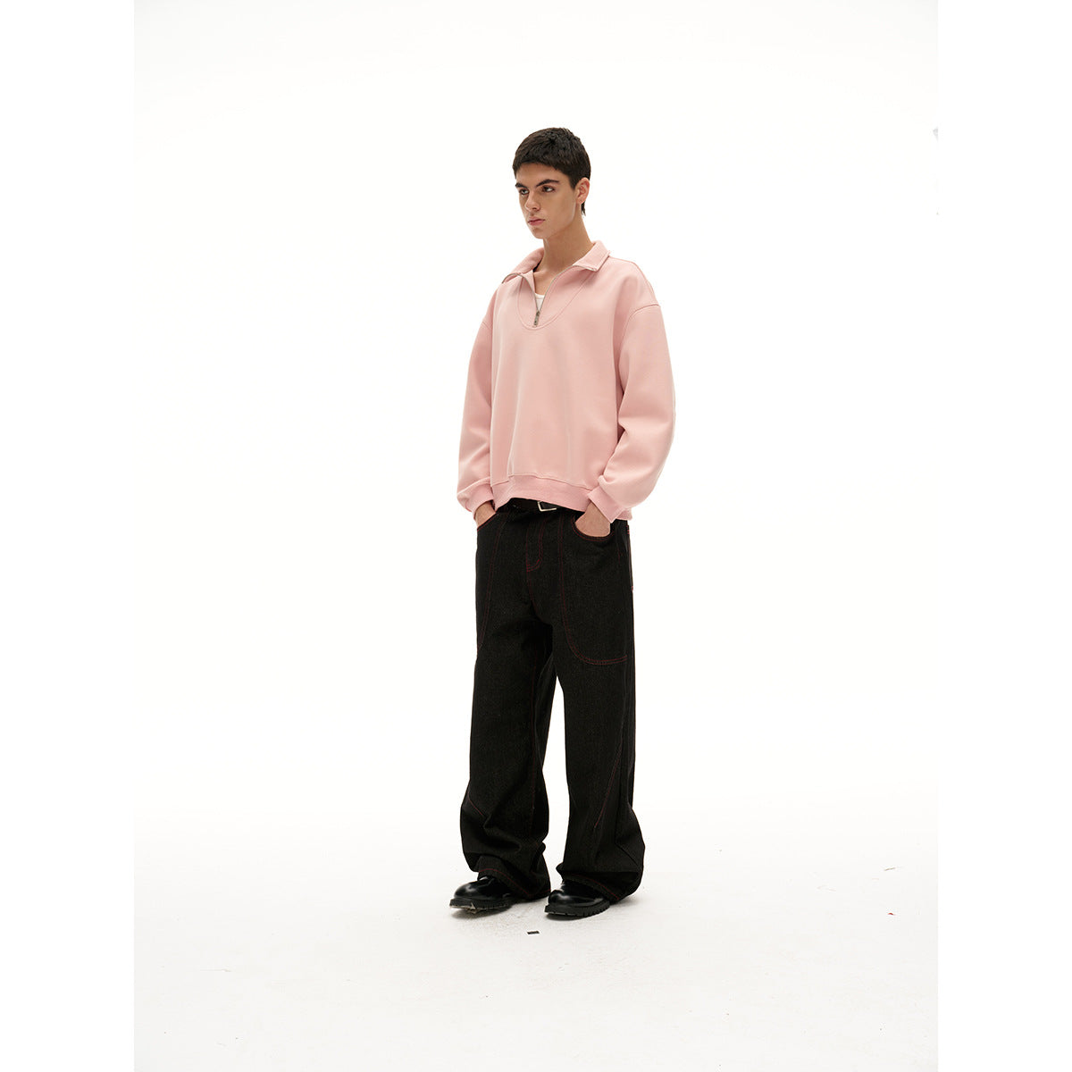 Model wearing a pale pink quarter-zip pullover with oversized black wide-leg pants and black shoes.