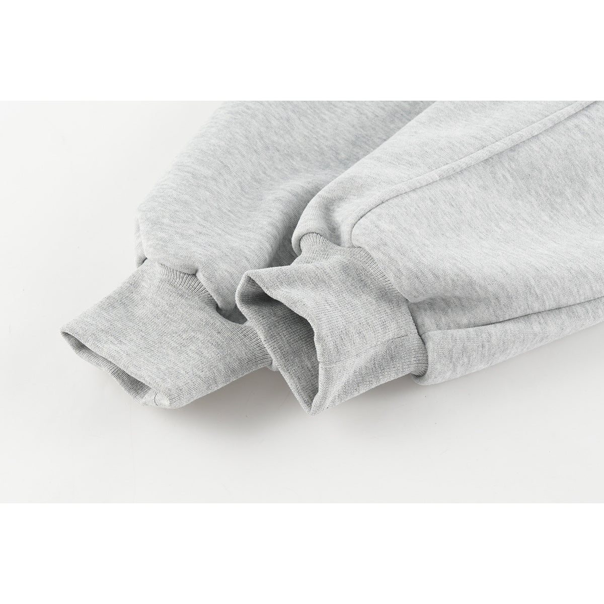 Close-up of a light gray sweatshirt sleeve and ribbed cuff, showing the fabric and seam construction.