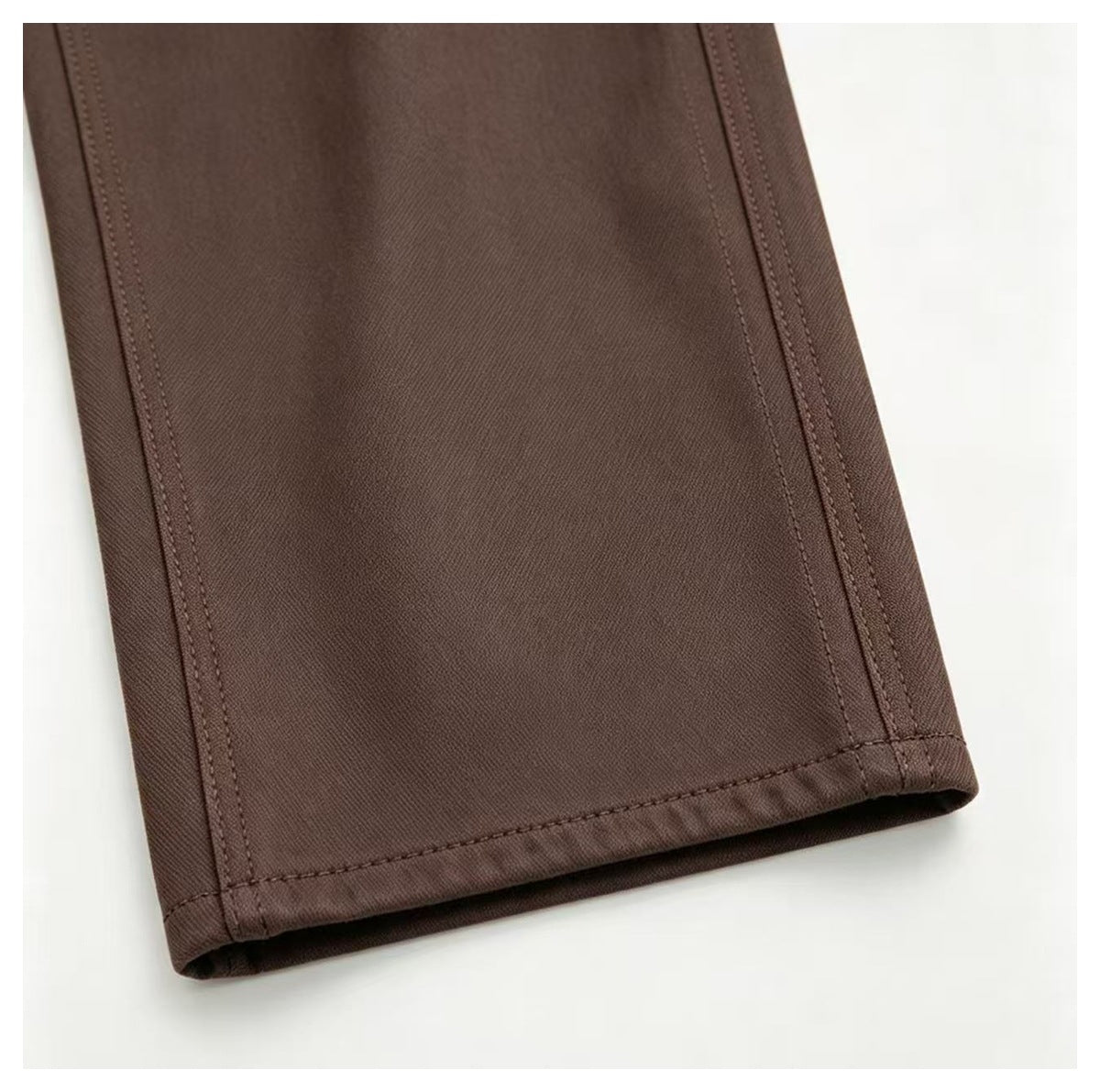 Close-up of a brown trouser leg hem showing the stitching and side seams.