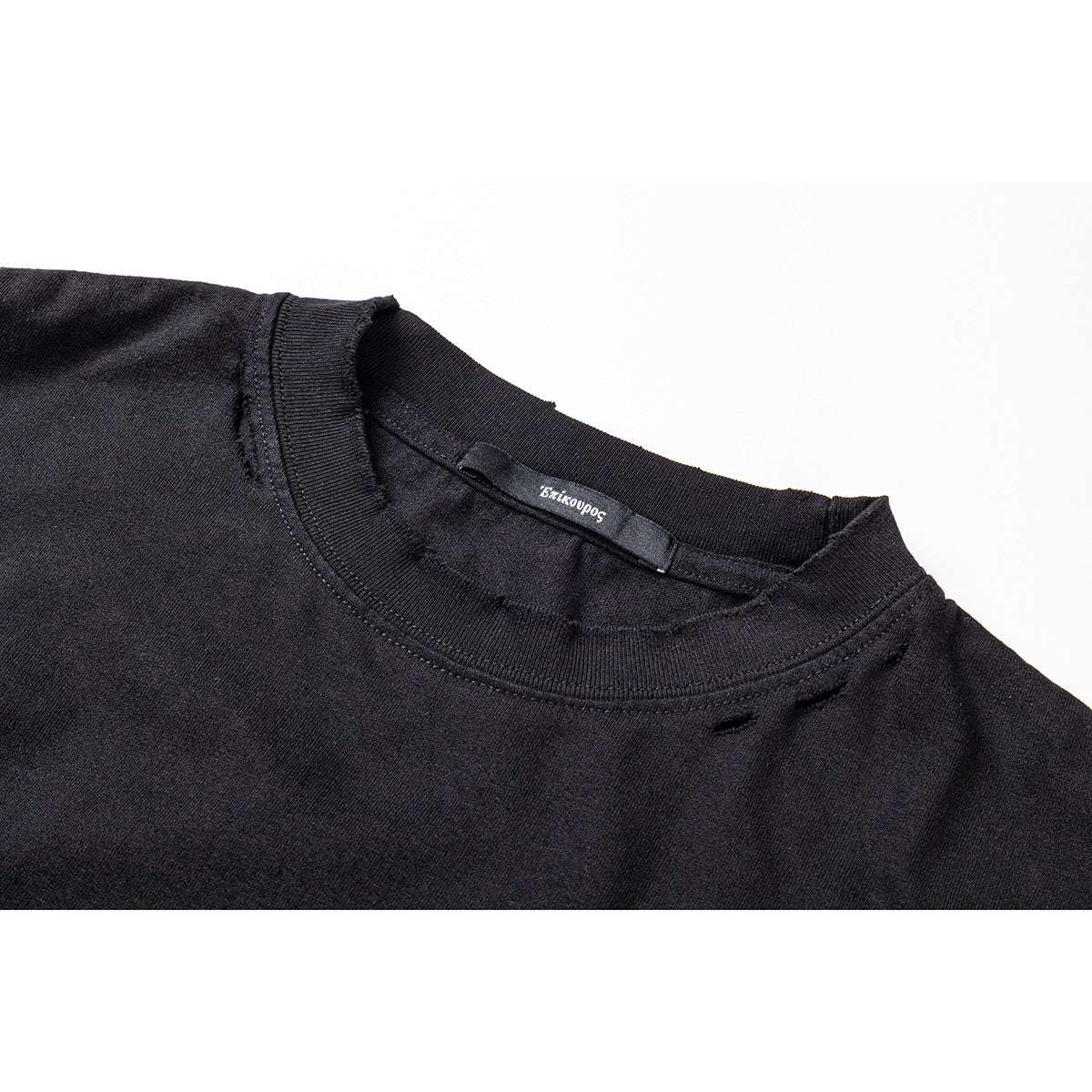 Close-up of a black crew-neck shirt showing the ribbed collar, inner label, and small distressed openings.