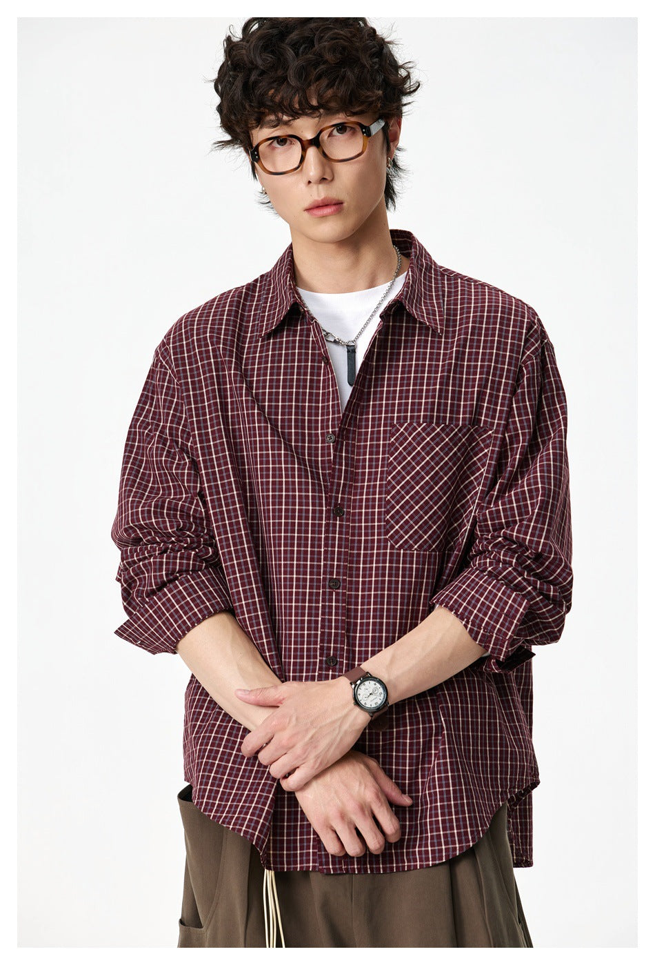 Model wearing a burgundy plaid button-up shirt with a diagonal-plaid chest pocket, shown from the waist up.