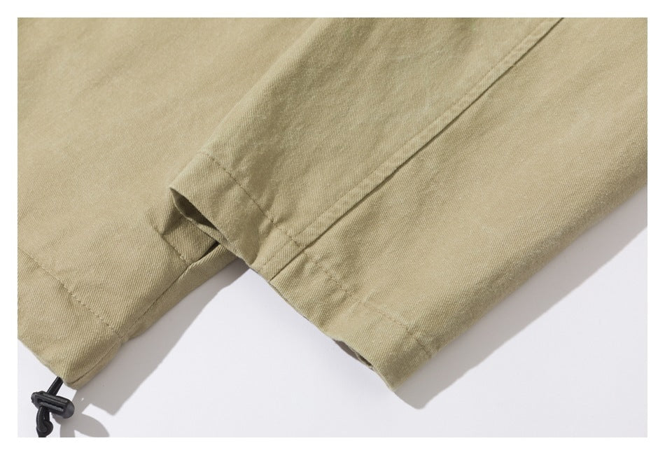 Close-up of a tan jacket sleeve and hem seams, with a black drawcord toggle visible.