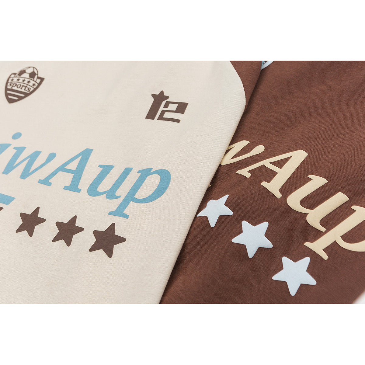 Close-up of cream and brown T-shirt chest graphics with blue lettering, stars, and small emblems printed on the fabric.