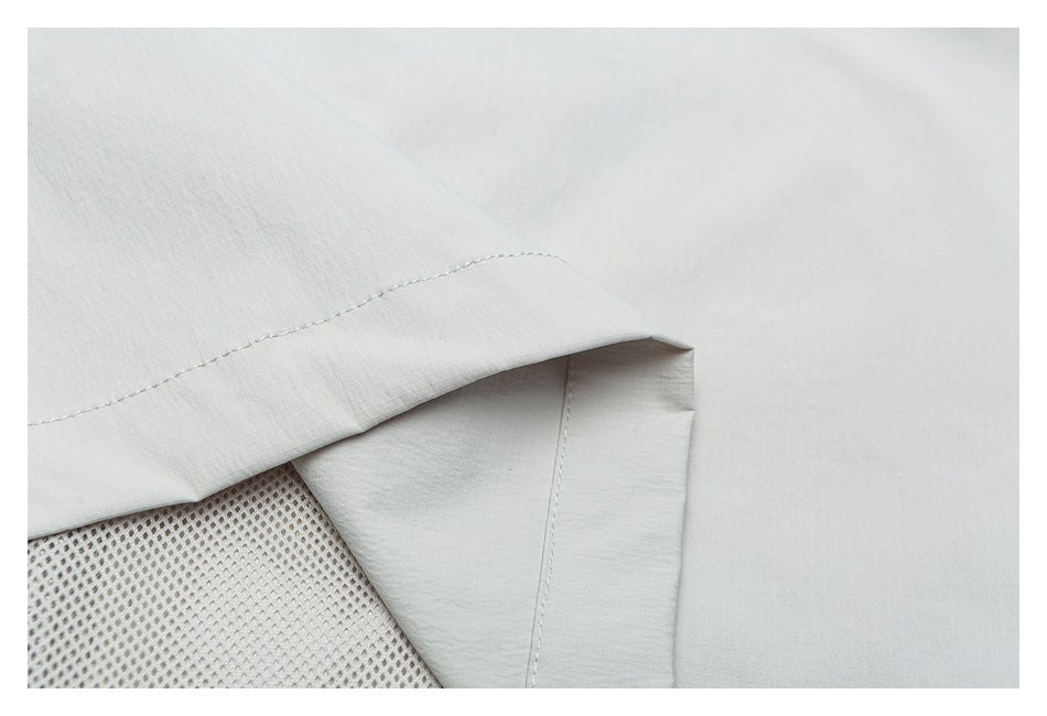 Close-up of pale gray garment construction with a folded edge and a section of mesh lining.