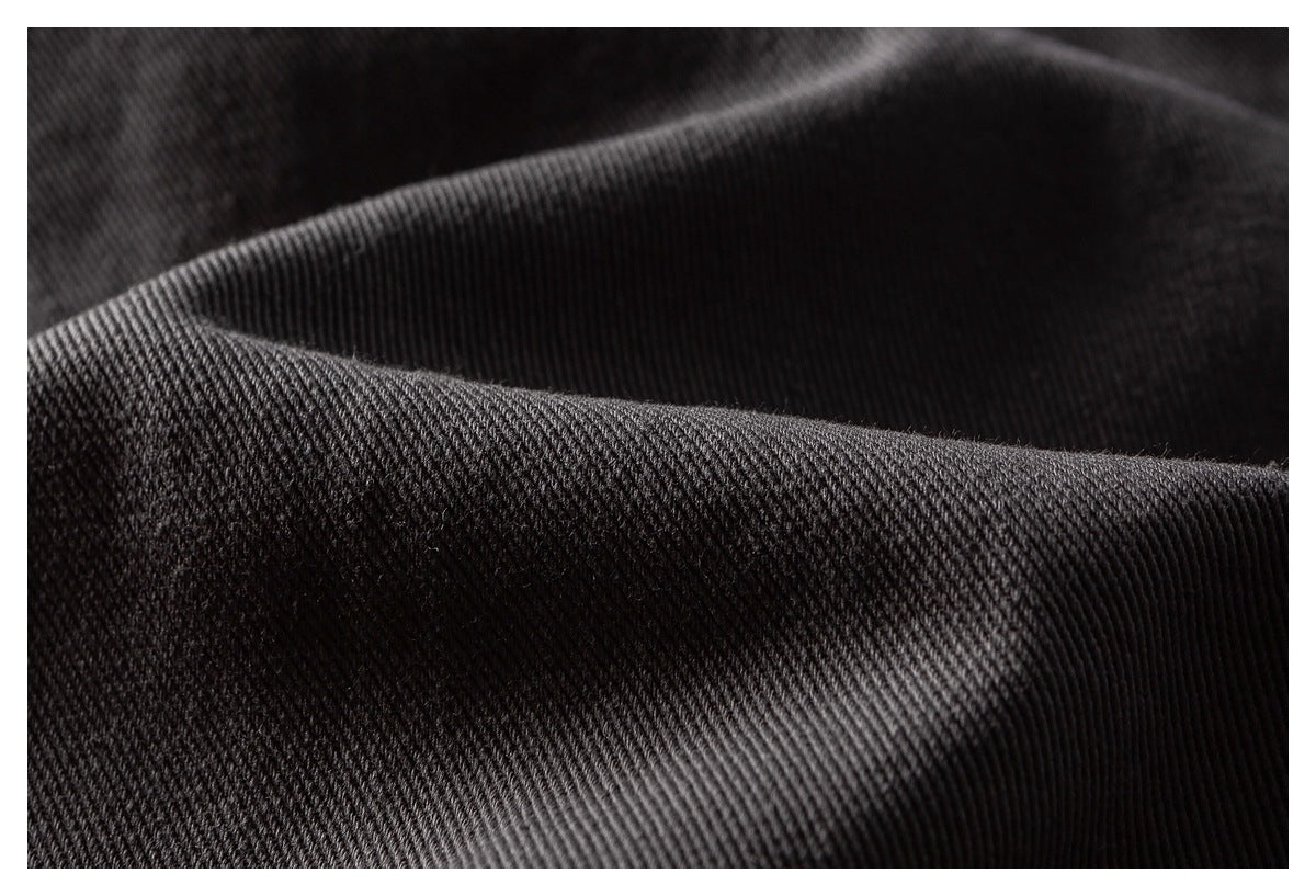 Close-up of dark charcoal fabric showing a fine diagonal twill weave and folded texture.