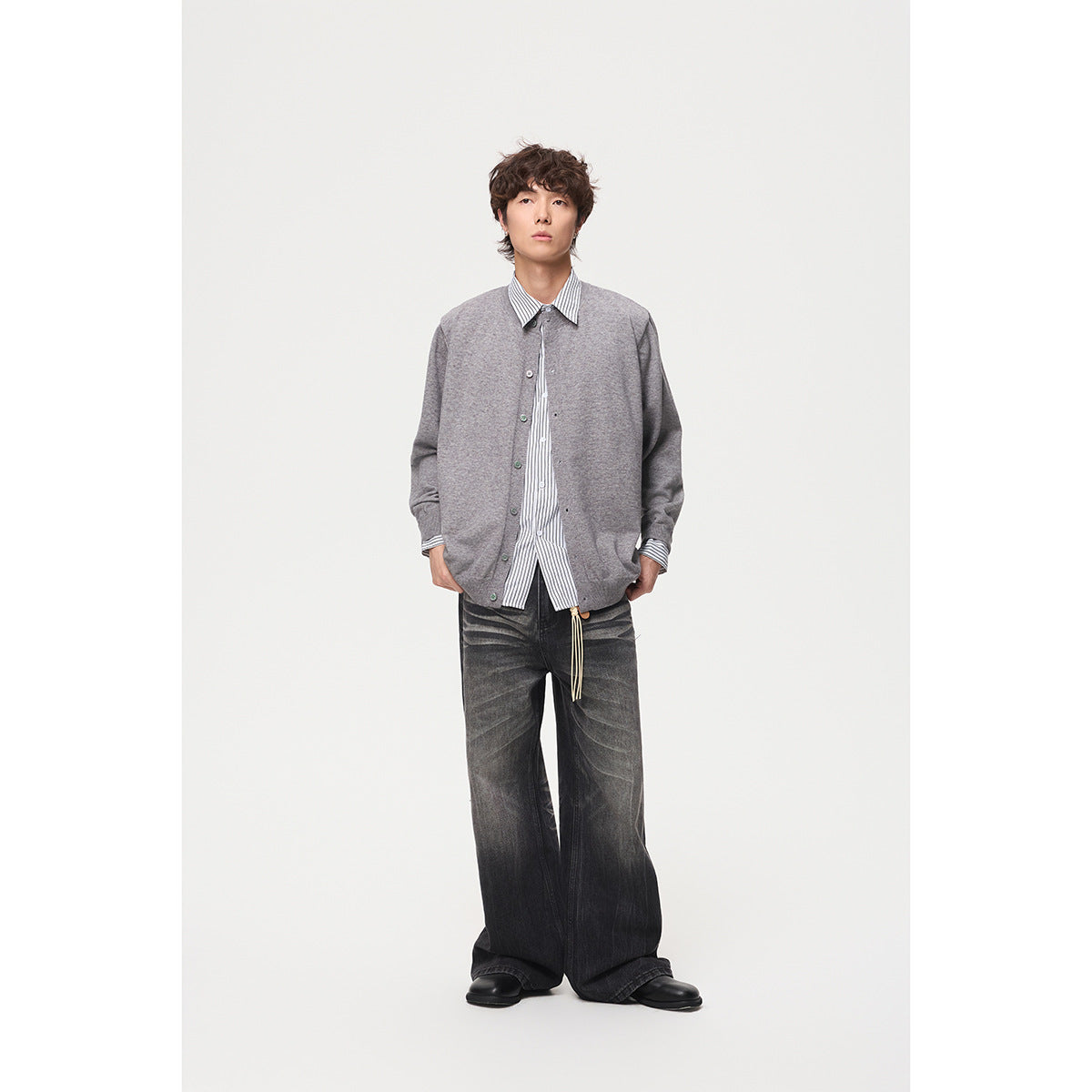 Full-length model wearing a gray button-front cardigan over a striped shirt with wide dark jeans.