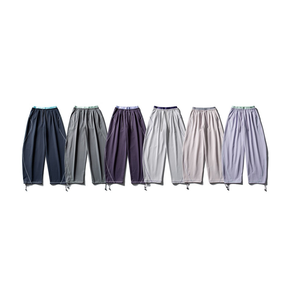 Six pairs of loose drawstring pants displayed together in navy, gray, purple, light gray, blush, and lavender.