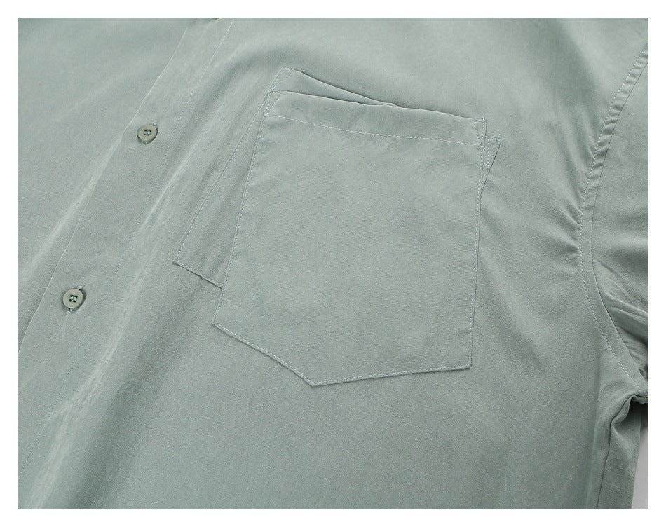 Close-up of the sage-green shirt's button placket and single chest pocket.