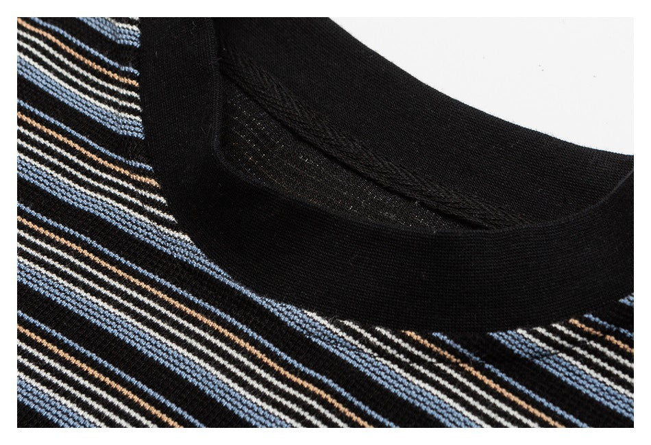 Close-up of the black ribbed crew neckline and blue, cream, and brown stripes on a black top.