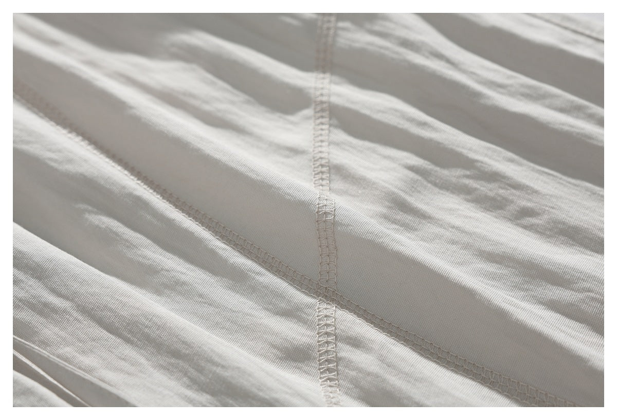 Close-up of cream-colored garment fabric with intersecting overlocked seams.