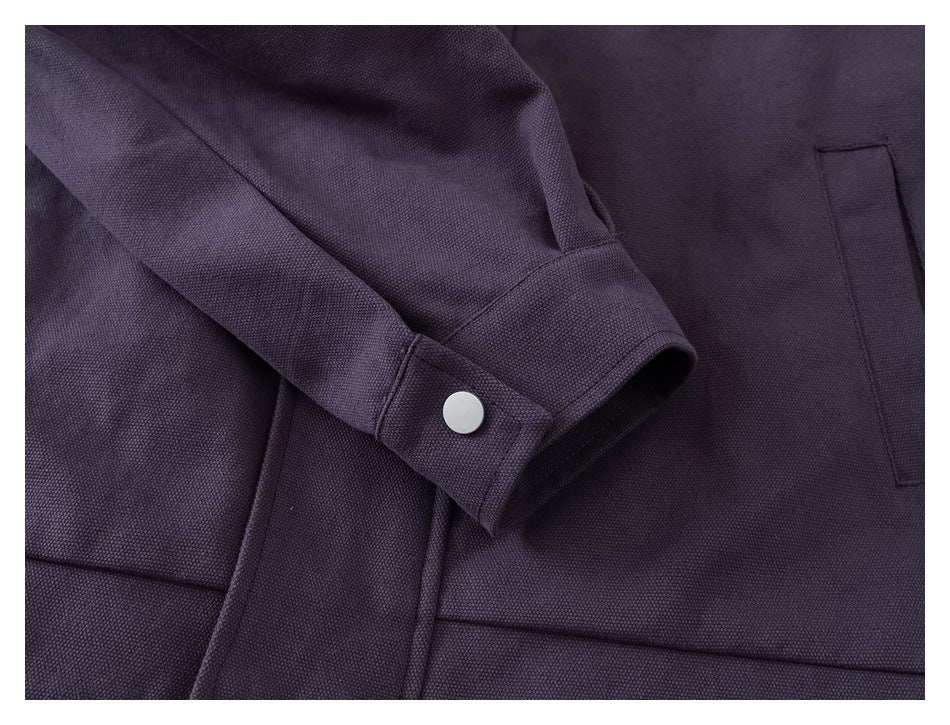 Close-up of a dark plum sleeve cuff with a silver snap and a nearby vertical pocket.