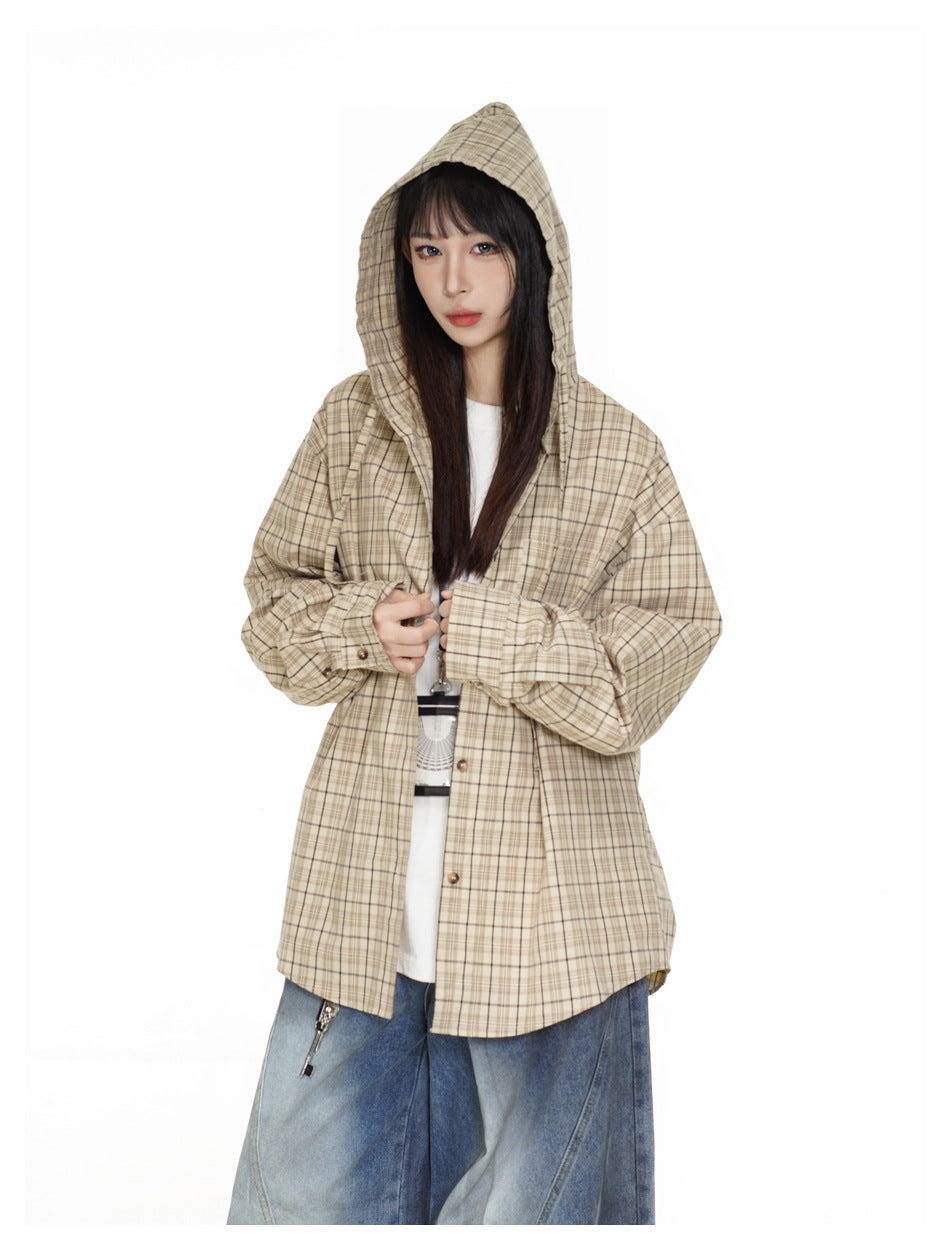 Model wearing a beige plaid hooded button-up shirt jacket over a white top and wide-leg blue jeans.