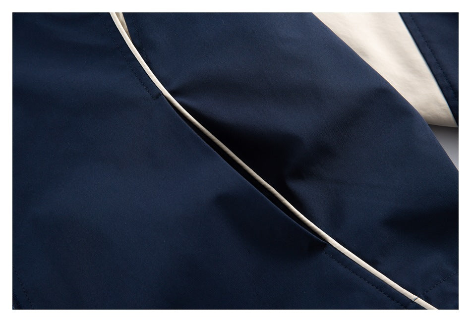 Close-up of navy jacket fabric with cream piping along a seam and panel.