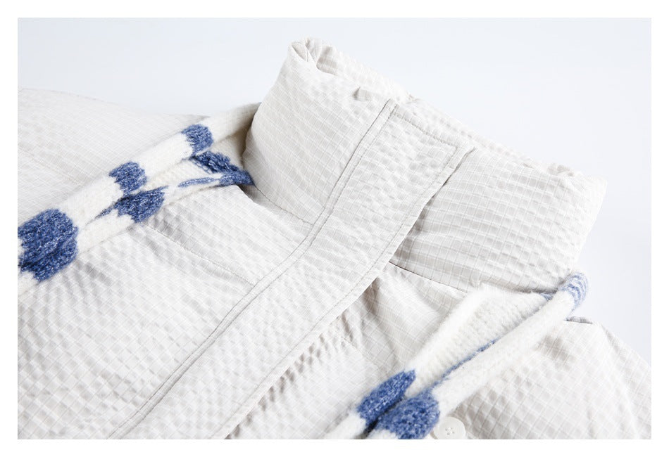 Close-up of the white jacket collar and front, with a blue-and-white patterned scarf draped across it.