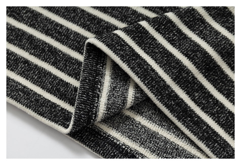 Folded edge of charcoal and cream striped knit fabric, showing the inside and finished seam.
