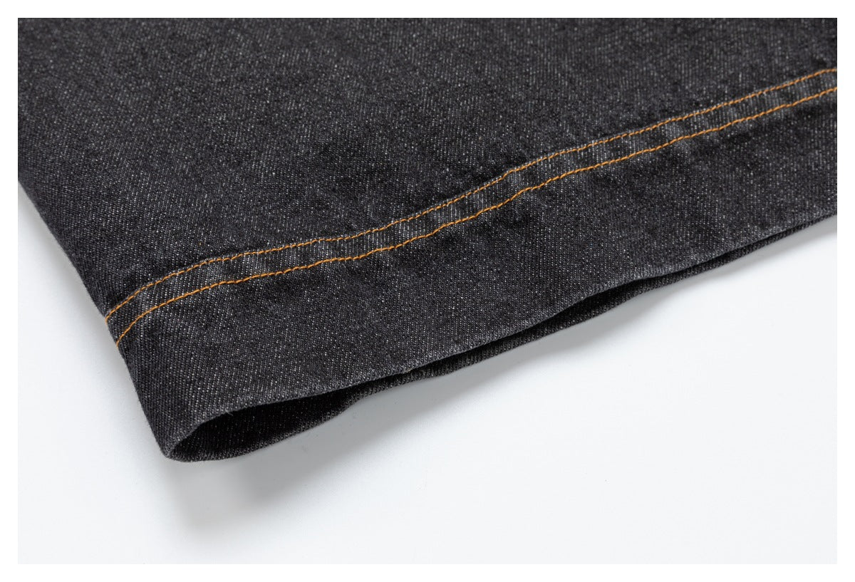 Close-up of a dark denim hem with parallel orange stitching.