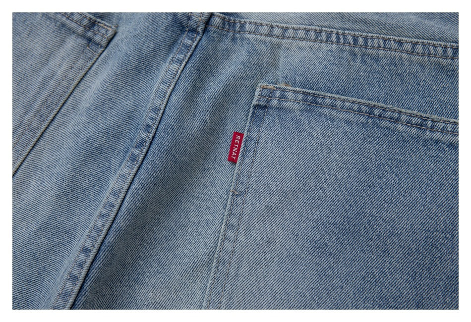 Close-up of a light blue denim back pocket with contrast stitching and a red woven tab.