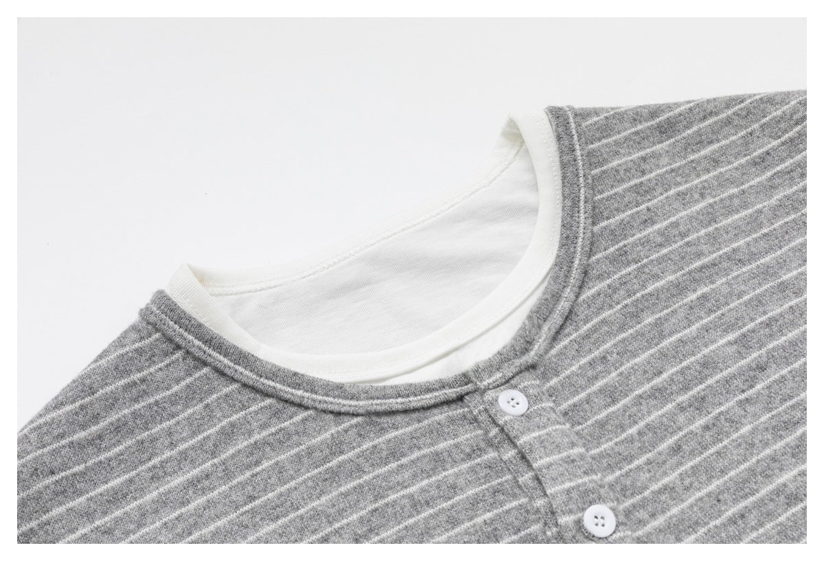 Angled close-up of the gray-and-white striped top's layered neckline and white buttons.