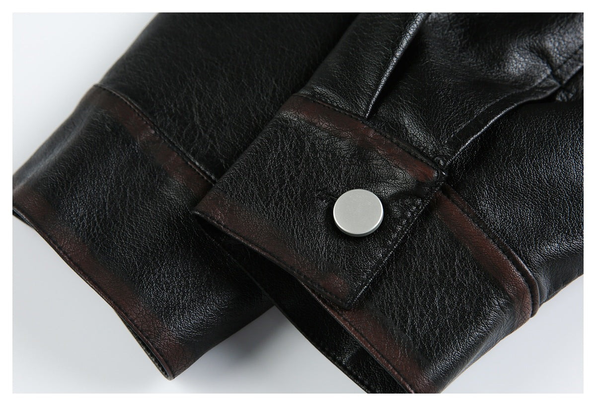 Close-up of a black leather-look jacket cuff with a silver snap and dark brown trim.