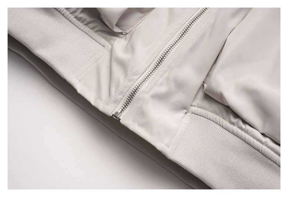 Close-up of the pale gray jacket's front zipper and ribbed hem.