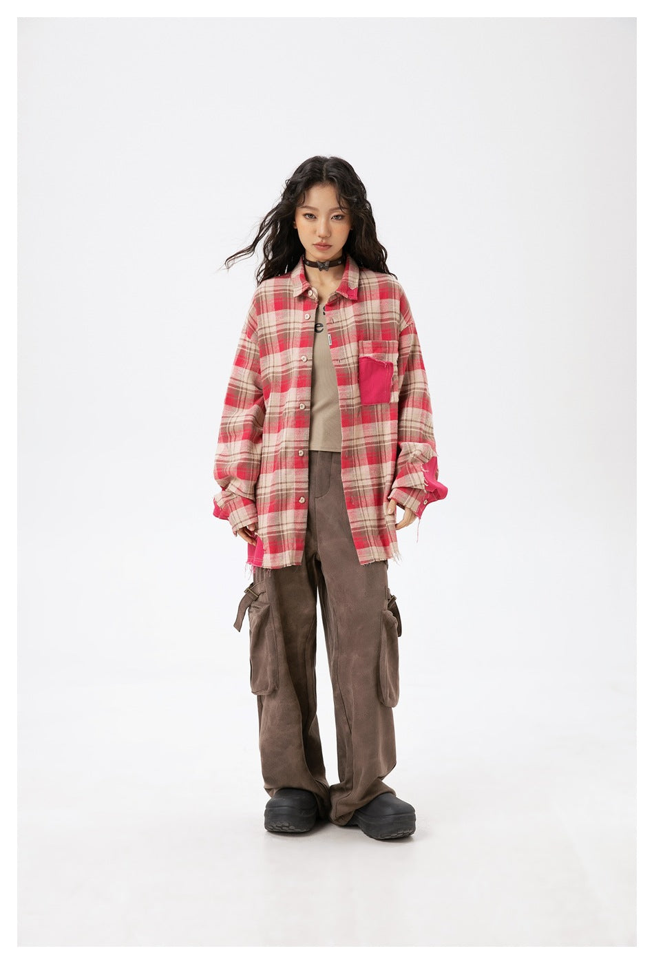 Model wearing open oversized plaid patchwork shirt over a tan top and brown cargo pants, full-length front view