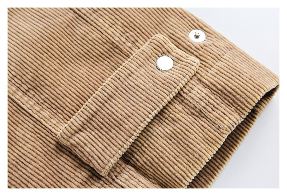 Close-up of a tan corduroy garment with a stitched tab and silver snap fastener.