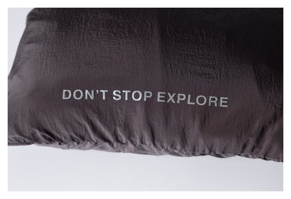 Close-up of dark crinkled fabric with “DON’T STOP EXPLORE” printed in light lettering.