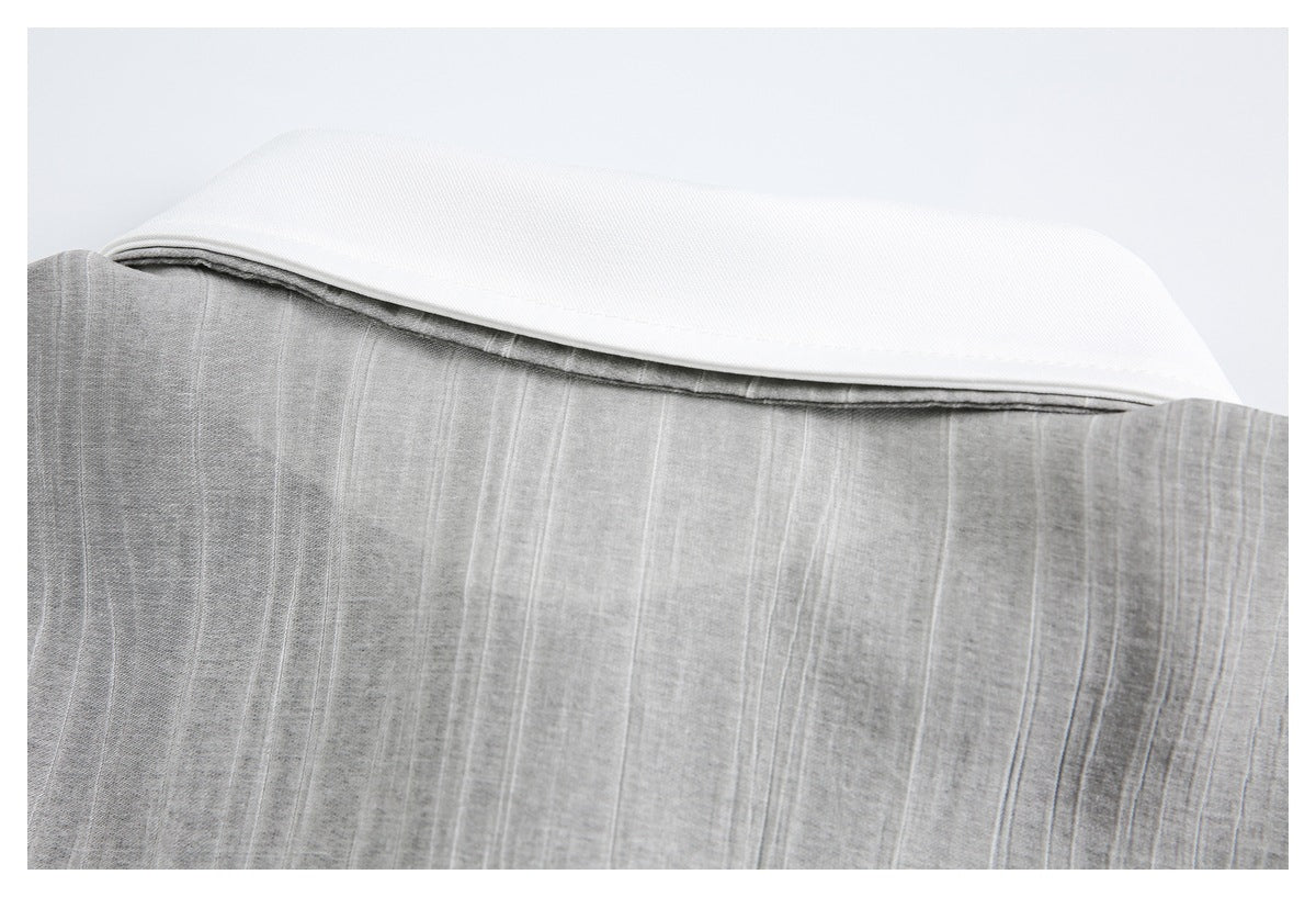 Close-up of a broad white band resting above gray fabric with subtle vertical stripes.