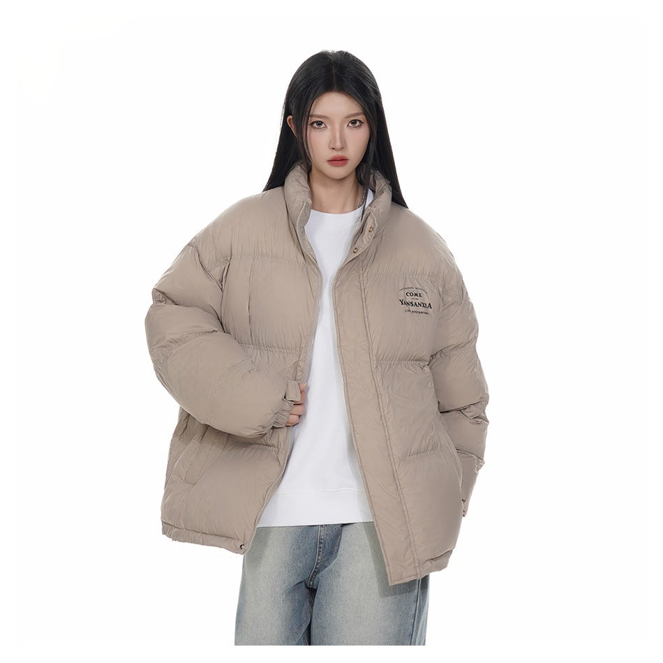 Model wearing an open light khaki puffer jacket over a white sweatshirt and light jeans