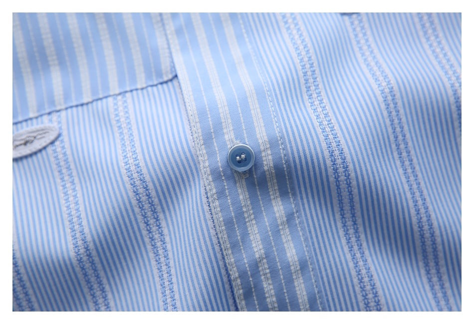 Close-up of a blue button on light blue and white striped shirt fabric.