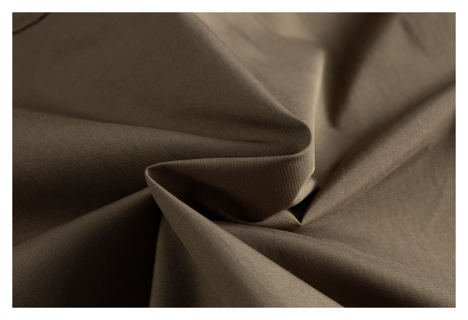 Close-up of taupe-brown jacket fabric arranged in soft folds.