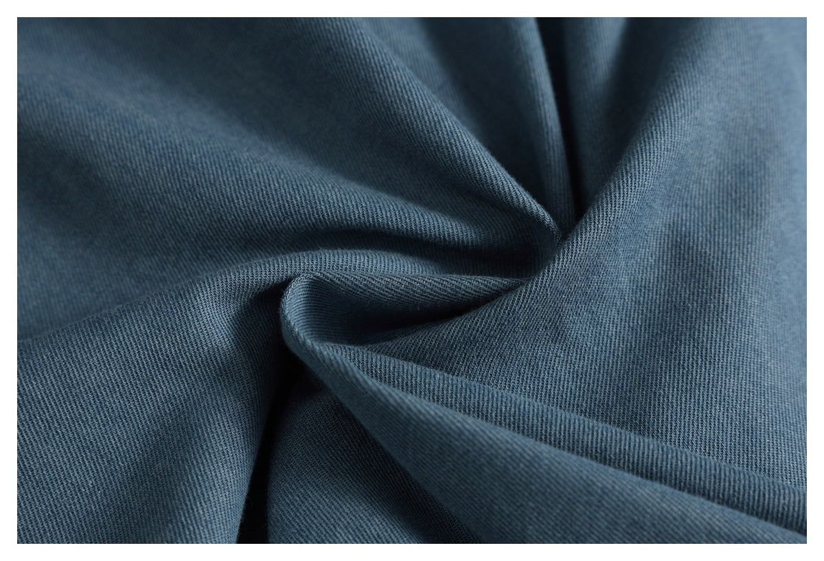 Close-up of blue denim fabric draped into folds, showing its diagonal weave.