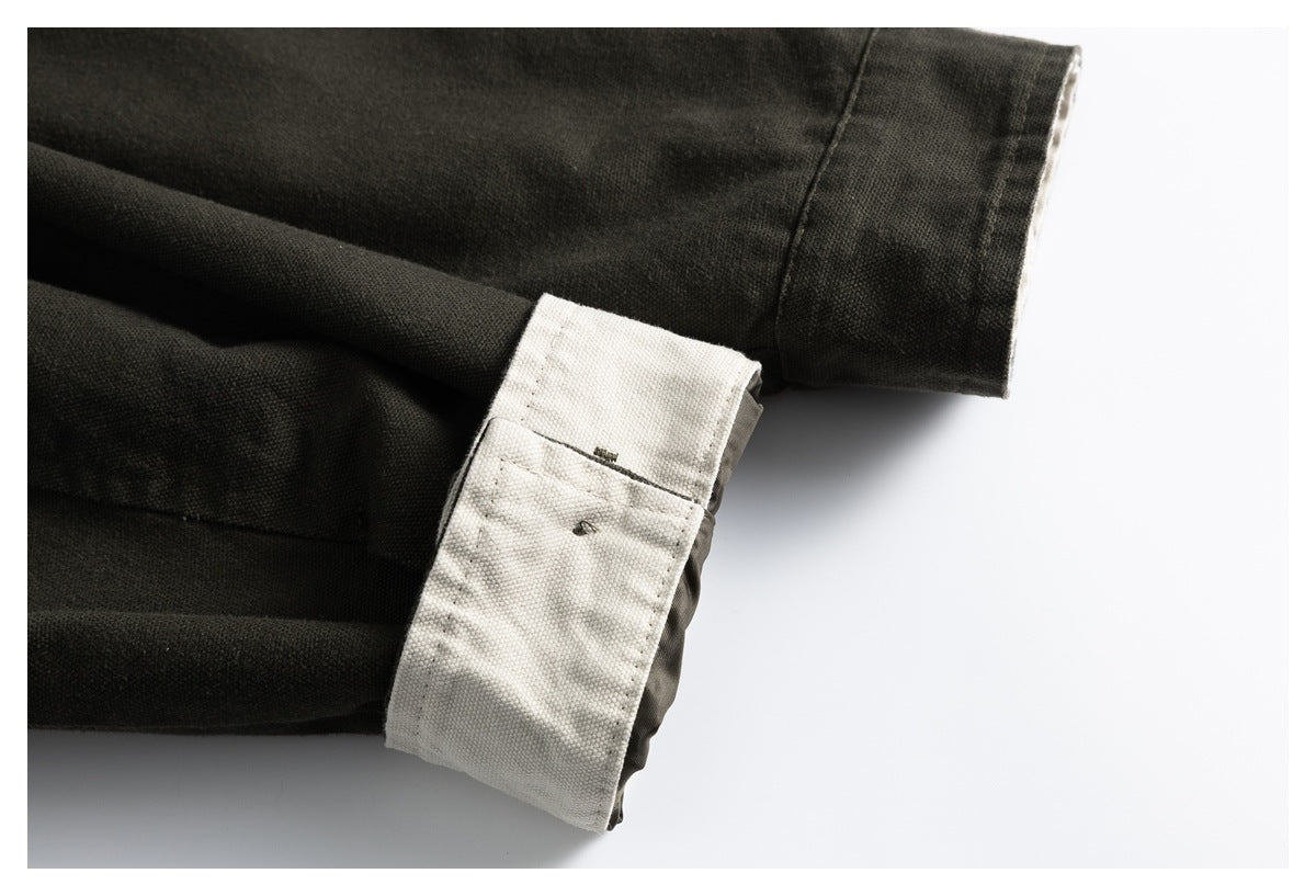 Close-up of a turned-back jacket sleeve cuff showing its cream lining against dark olive fabric.