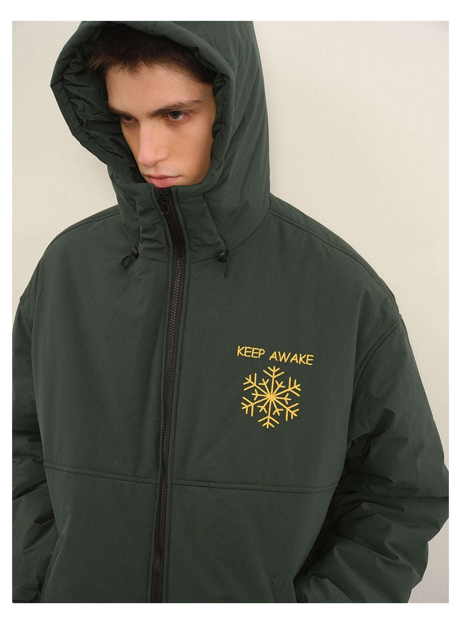 Close view of a dark green hooded jacket with yellow “KEEP AWAKE” lettering and snowflake embroidery.