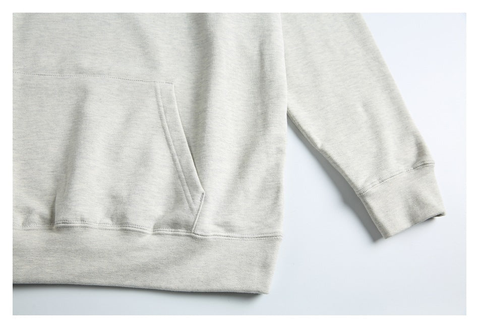 Close-up of a light gray hoodie showing the kangaroo pocket, ribbed hem, and sleeve cuff.