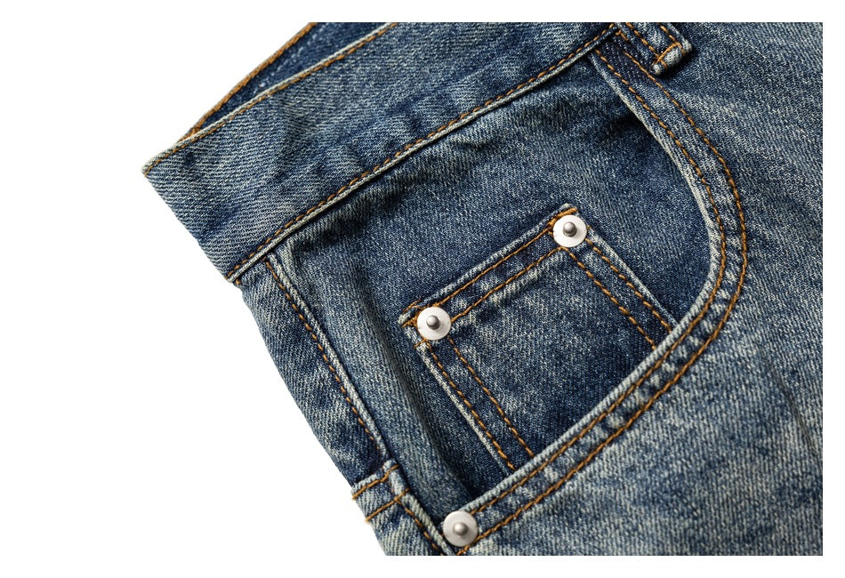 Close-up of a front coin pocket and curved pocket stitching on blue faded jeans.
