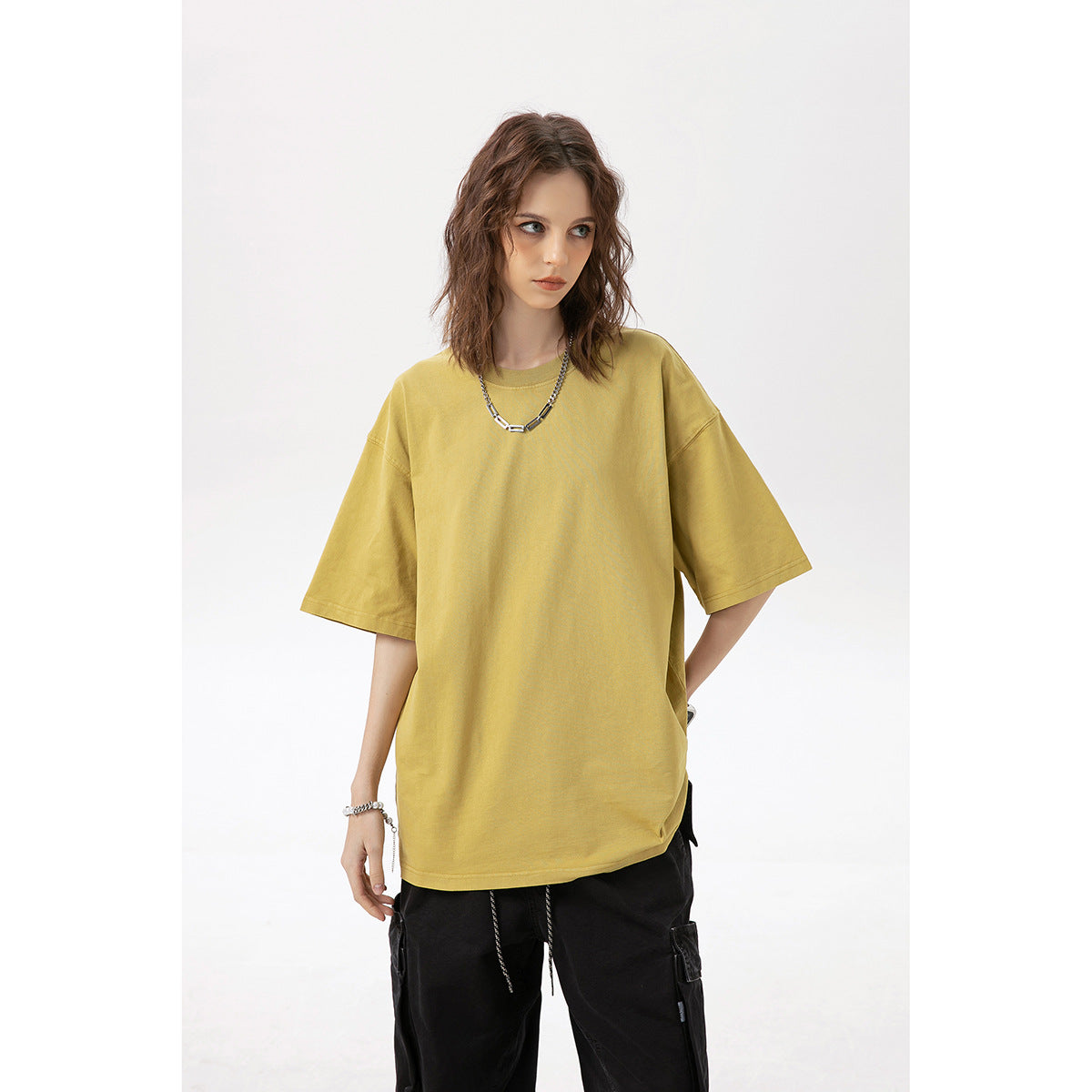 Model wearing an oversized mustard-yellow short-sleeve T-shirt with black pants.